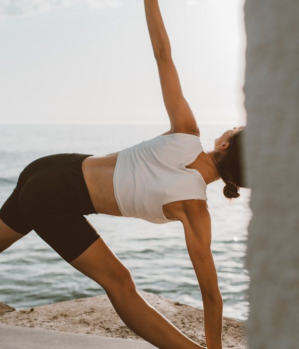 Person stretching outdoors during sunrise with a calm expression.