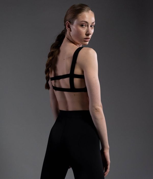 Woman in a graceful yoga pose in a dark, minimalist studio.
